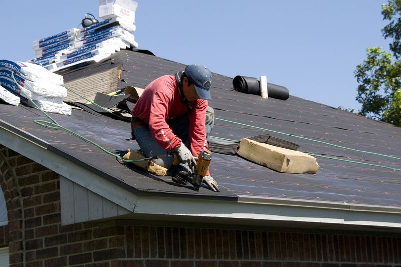 Roofer installing asphalt shingles on a house