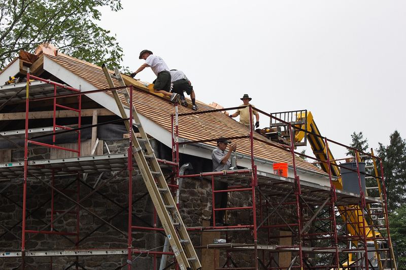 Roofers installing shingles and gutters